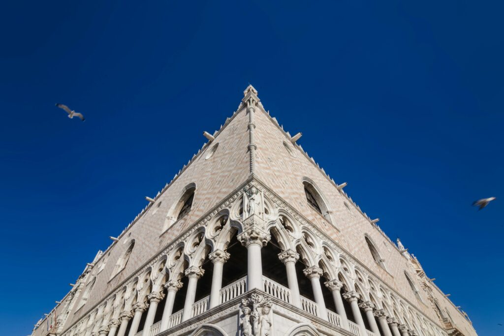 Corner of Gothic palace under blue sky with seagulls.
