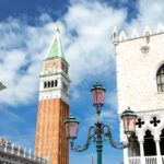 Venice square with tower and winged lion statue.